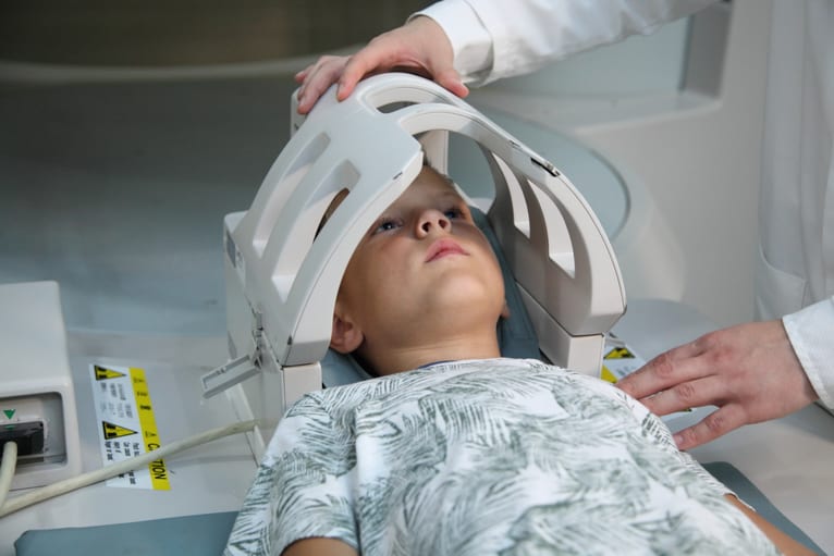 criança com a cabeça dentro do aparelho de tomografia