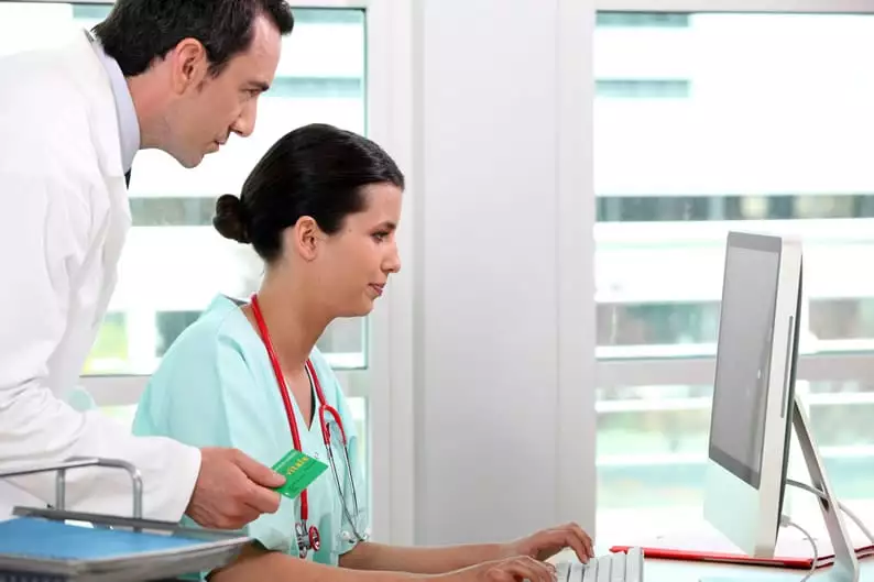 Médicos vendo exames de saúde ocupacional no computador